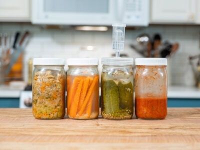 Fire glas med grøntsager står på et køkkenbord til fermentering