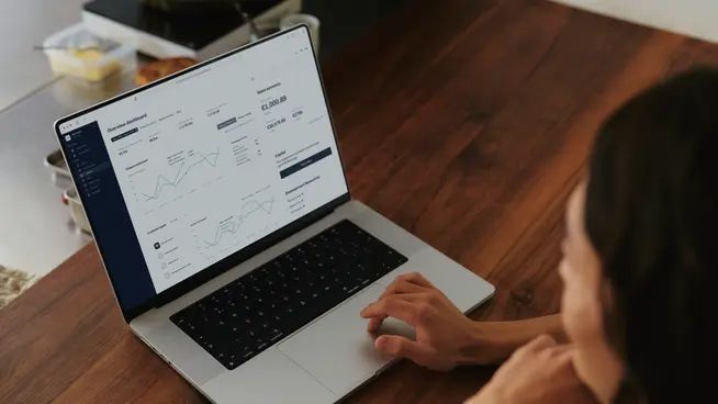 En caféejer analyserer økonomiske data og salgstal på sin bærbare computer.